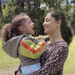 Dra Luciana com criança no colo, ambas sorrindo